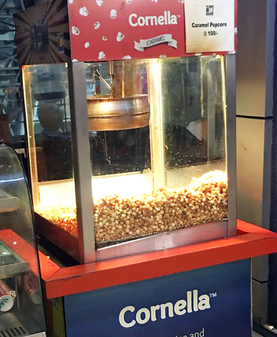 A Cornella popcorn popper at a cinema counter
