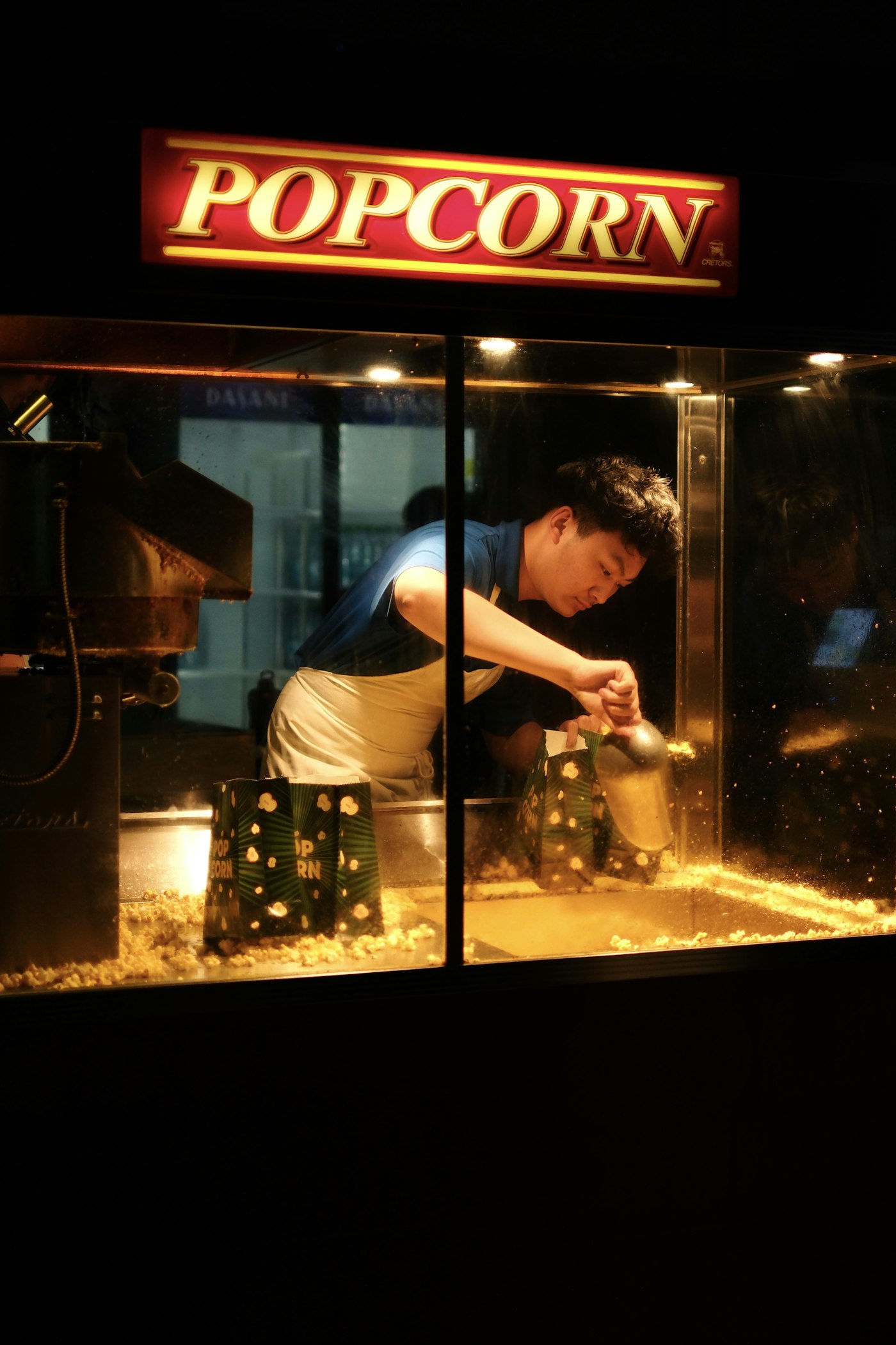 Fresh popcorn being bagged at a glowing popcorn machine